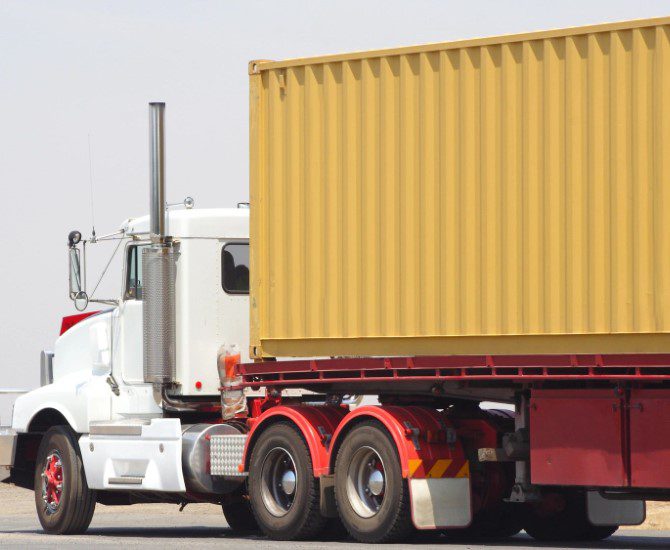 A semi truck with its trailer parked on the side of the road.