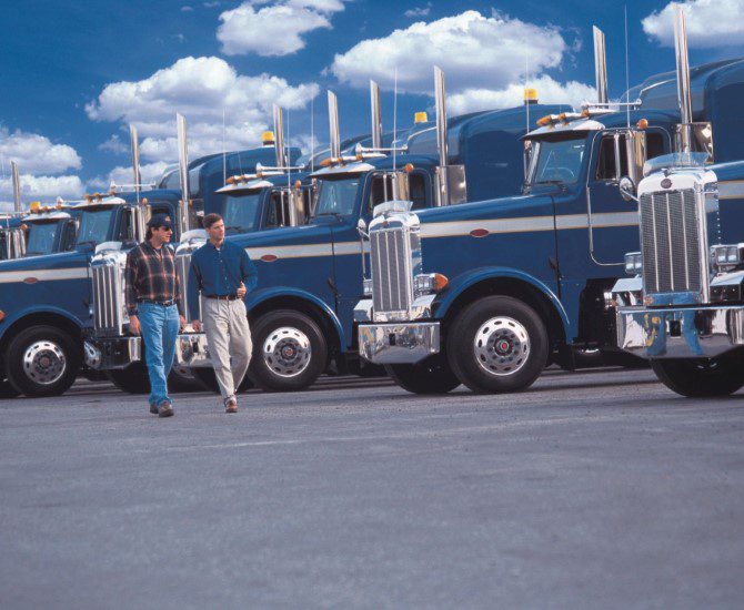 A man standing in front of a row of large trucks.