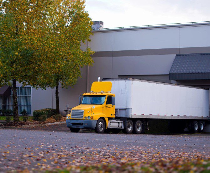 A yellow and white truck parked in front of a building.