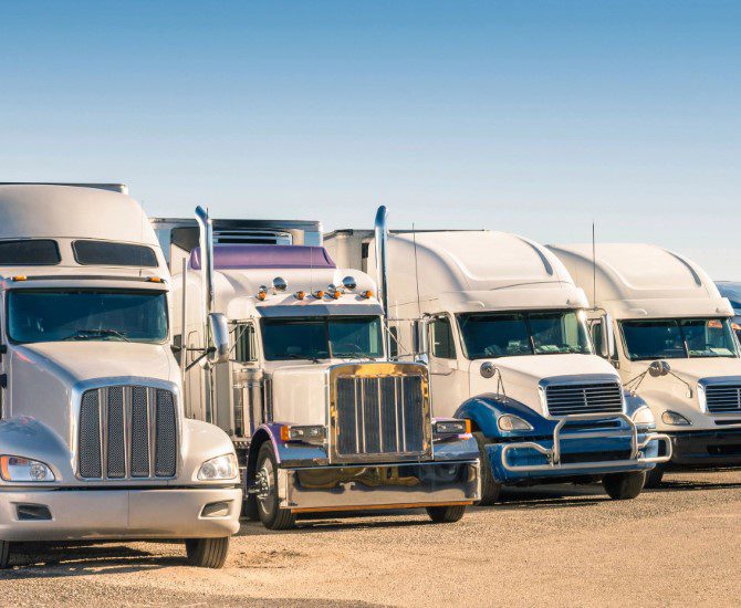 A row of semi trucks parked in a lot.